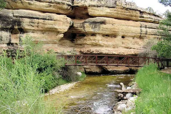 Medicine Lodge Archaeological Site 13 nature trail bridge over creek near rock formation at medicine lodge archaeological site in wyoming