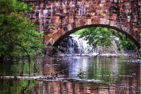 waterfall behind a stone bridge at a state park in arkansas