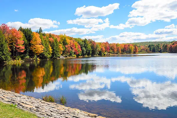 colorful trees and clouds reflected on a lake in a state park near carlisle pennsylvania