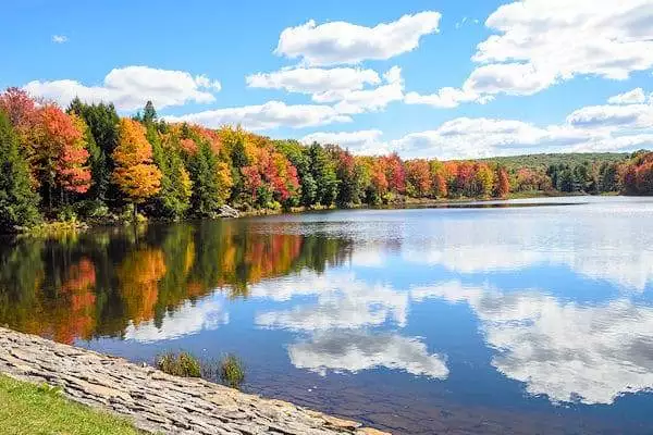 colorful trees and clouds reflected on a lake in a state park near carlisle pennsylvania