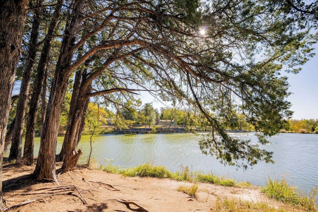sun peeking through the trees by a lake in boiling springs state park in oklahoma