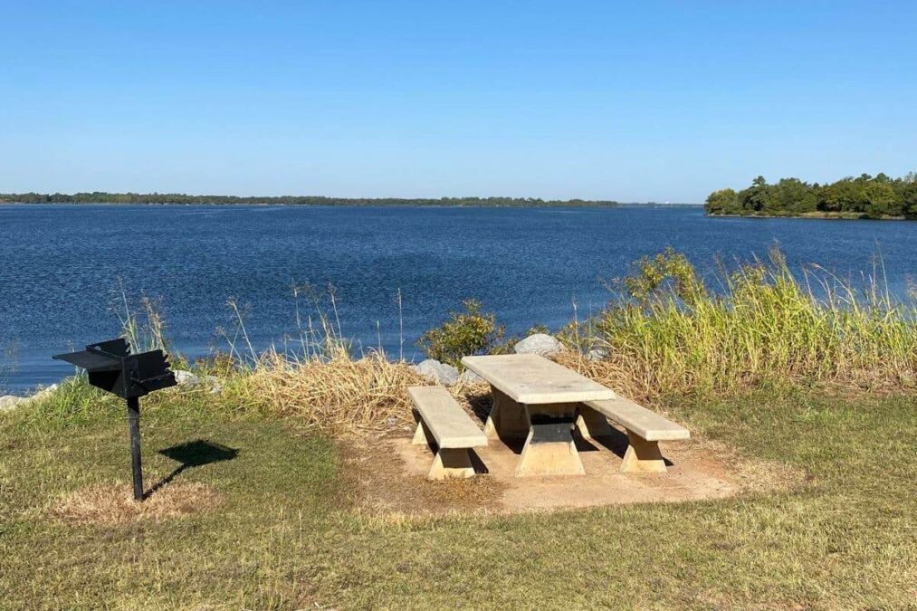 picnic table and grill next to the lake at fort cobb state park in oklahoma
