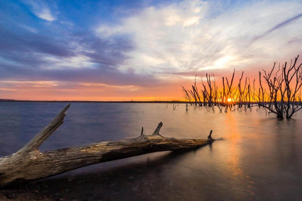 sunset over a lake in a state park near dodge city kansas