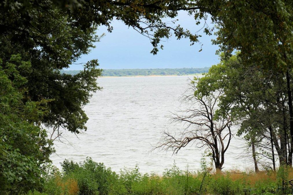 view of the water through the trees at lake texoma state park in oklahoma