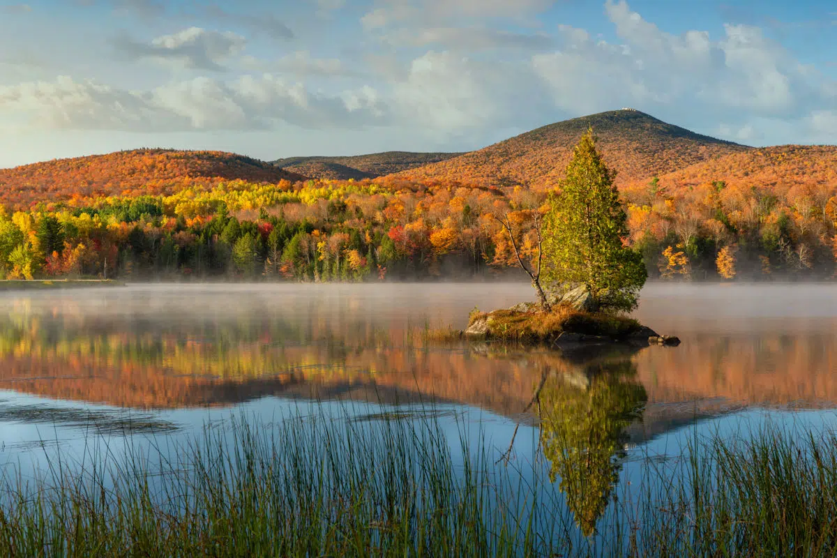 fall foliage reflected on a lake in the morning at a state park near rutland vermont