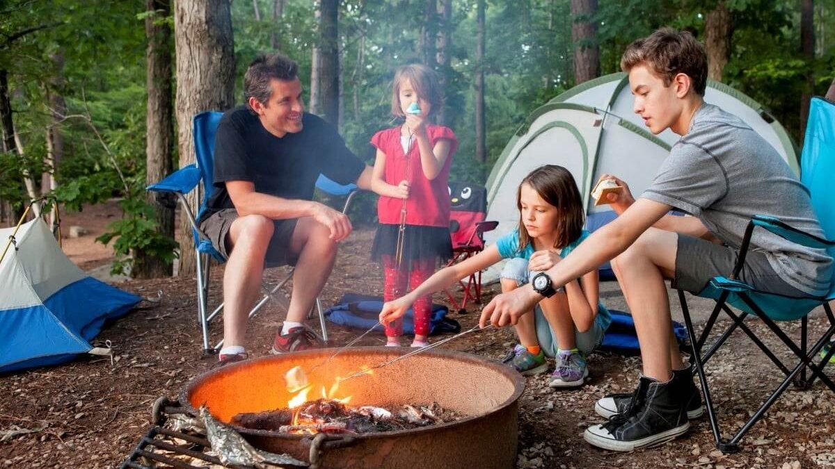 father sitting with his kids in front of a campfire