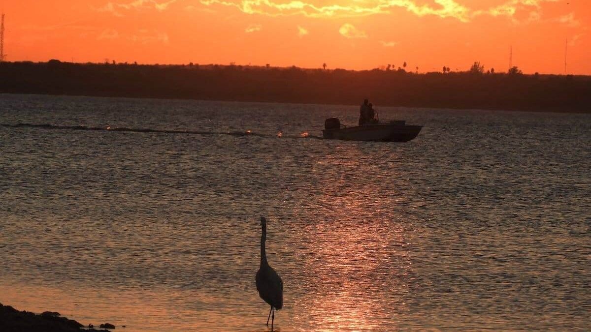 Boat on Falcon International Reservoir at Falcon State Park at sunset.