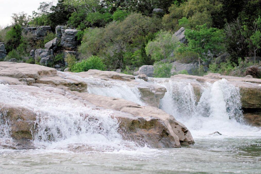 water from the Pedernales River falls over rocks at Pedernales Falls State Park