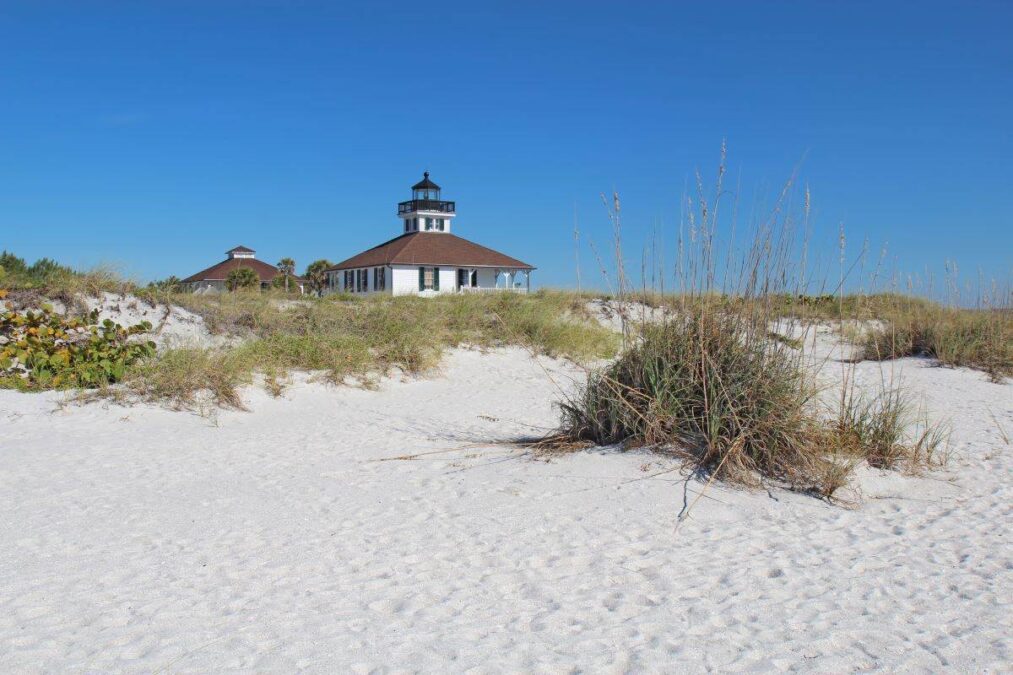 A lighthouse stands atop a sand dune in a State Park.