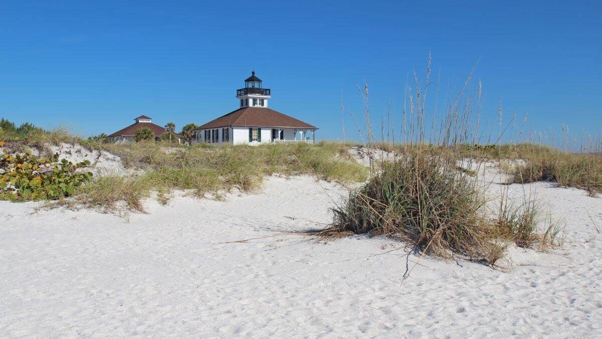 A lighthouse stands atop a sand dune in a State Park.