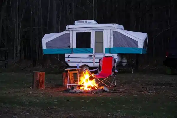 pop-up camper parked at a state park behind a campfire
