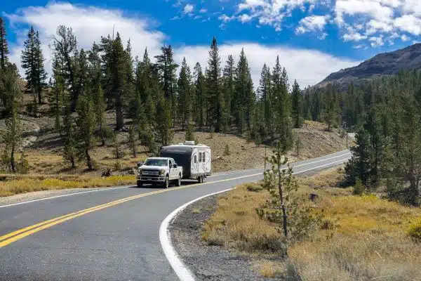 Truck towing a camper on the highway through the Sonora Pass on a sunny day, Sierra mountains