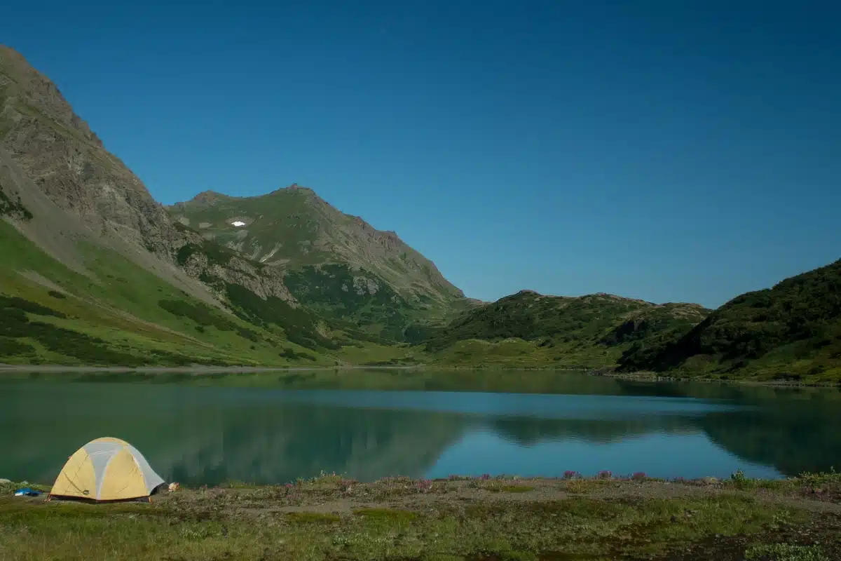 person camping in a tent by a lake at Kachemak Bay State Park