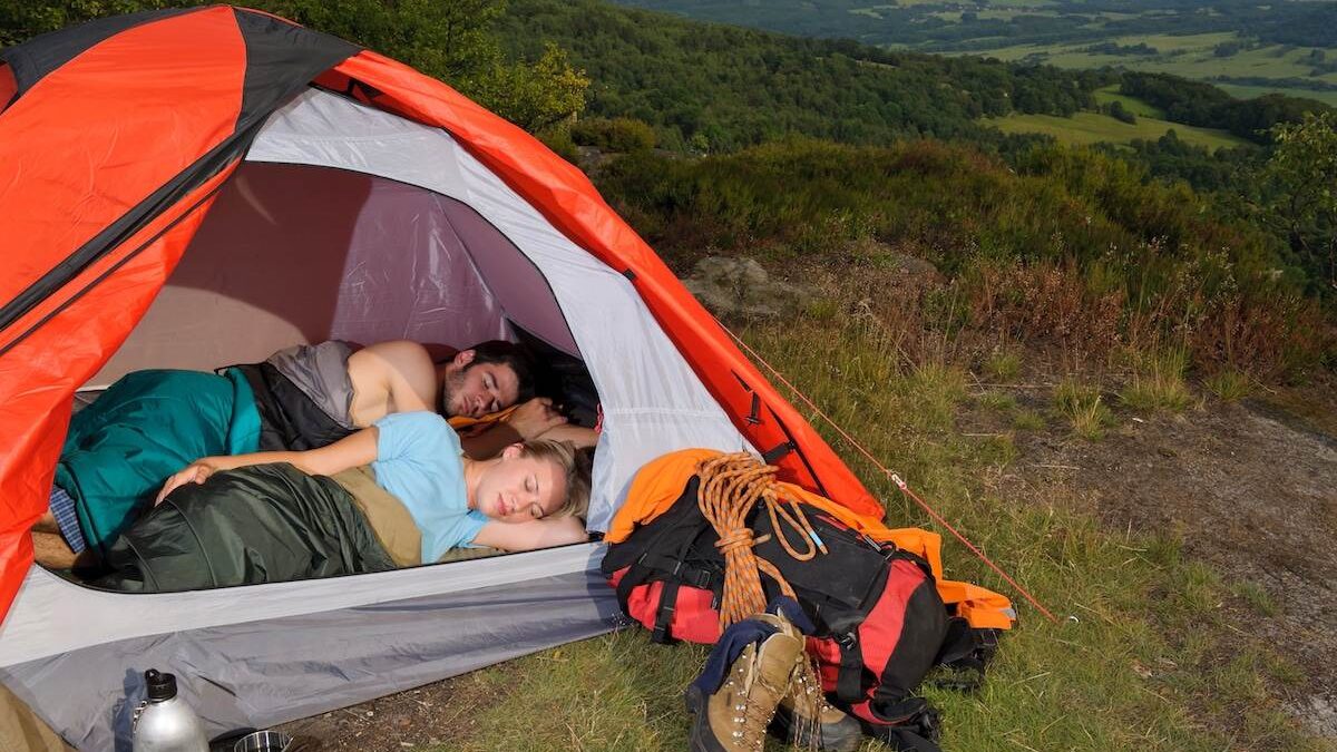 A couple sleeping on a camping mattress in a tent