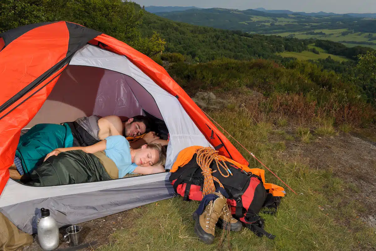 A couple sleeping on a camping mattress in a tent