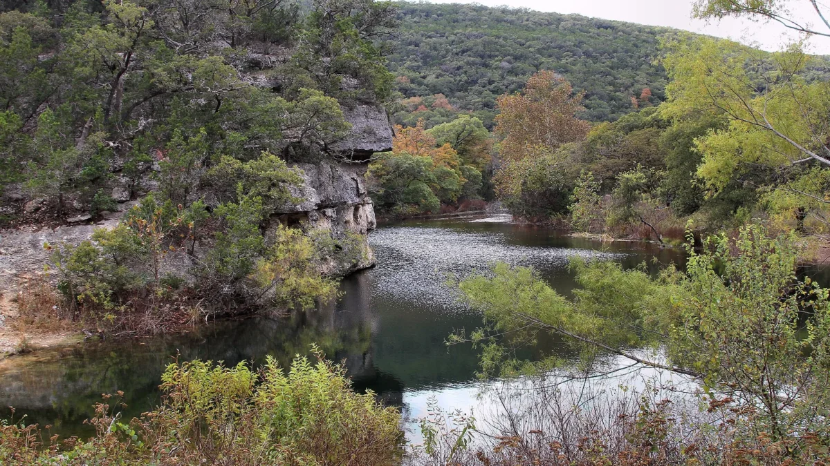 Lost Maples State Natural Area 64 Sabinal River pool below a limestone bluff and autumn-tinged hills, Lost Maples State Natural Area, Texas