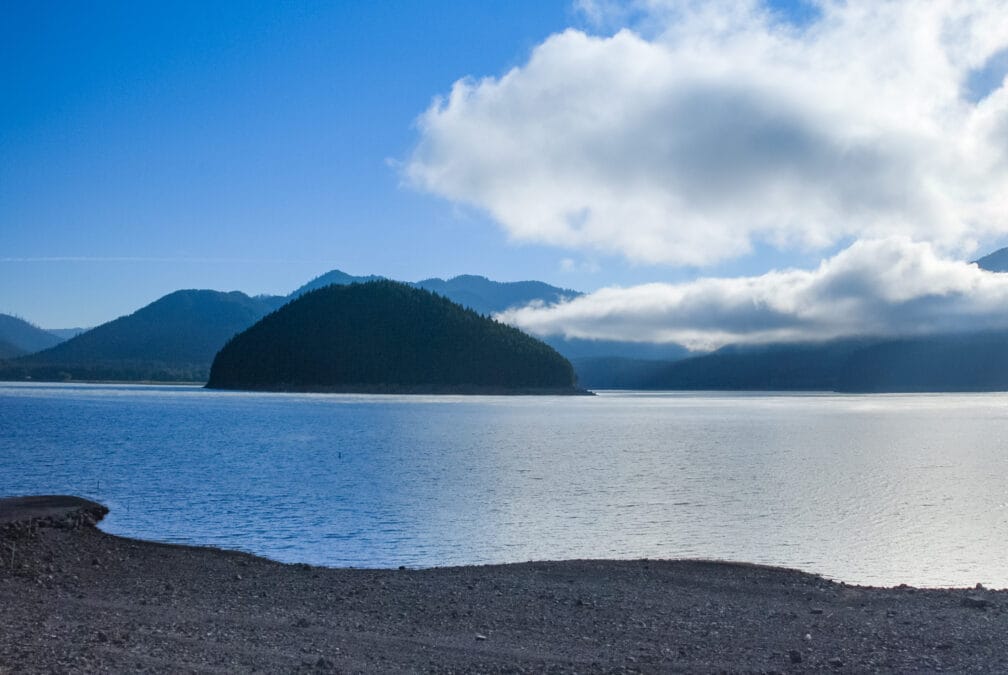 Detroit Lake seen from Mongold Day-Use Area's beach, with a forested island and the Cascade foothills in Marion County, Oregon