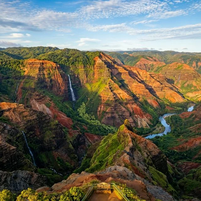 Dramatic aerial view of Waimea Canyon with red volcanic rock walls and waterfalls on Kauai Hawaii